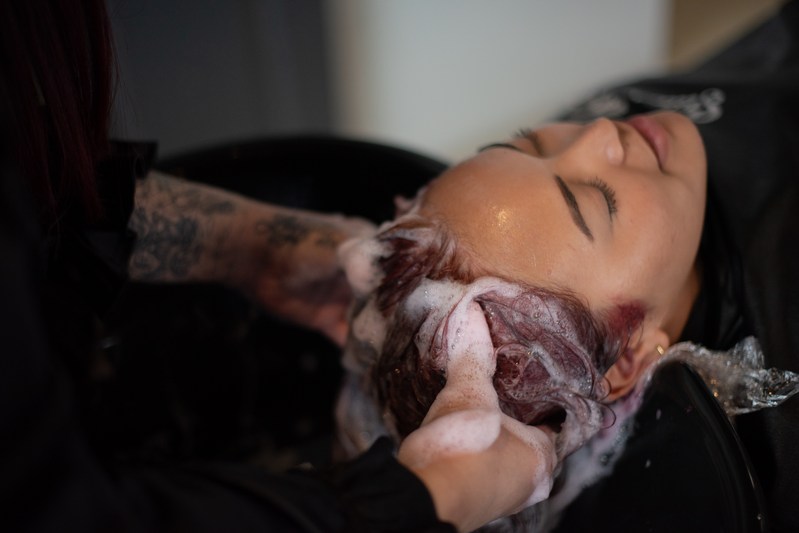 A Salon Fusion stylist rinsing a client's color at the shampoo bowl
